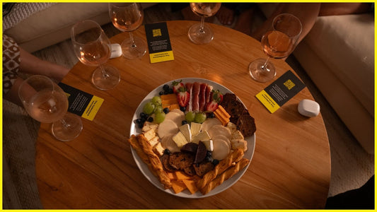 A group of friends gathered for a cozy night in, sharing wine and charcuterie with The Collectors Stories game cards on the table.