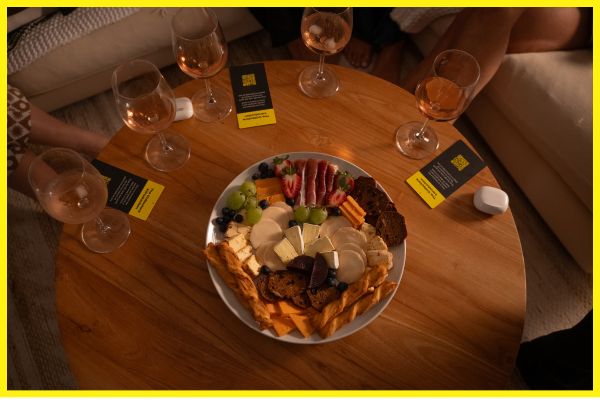 Game night table with The Collector’s Stories, wine, share plate, and headphones — setting the scene for connection.